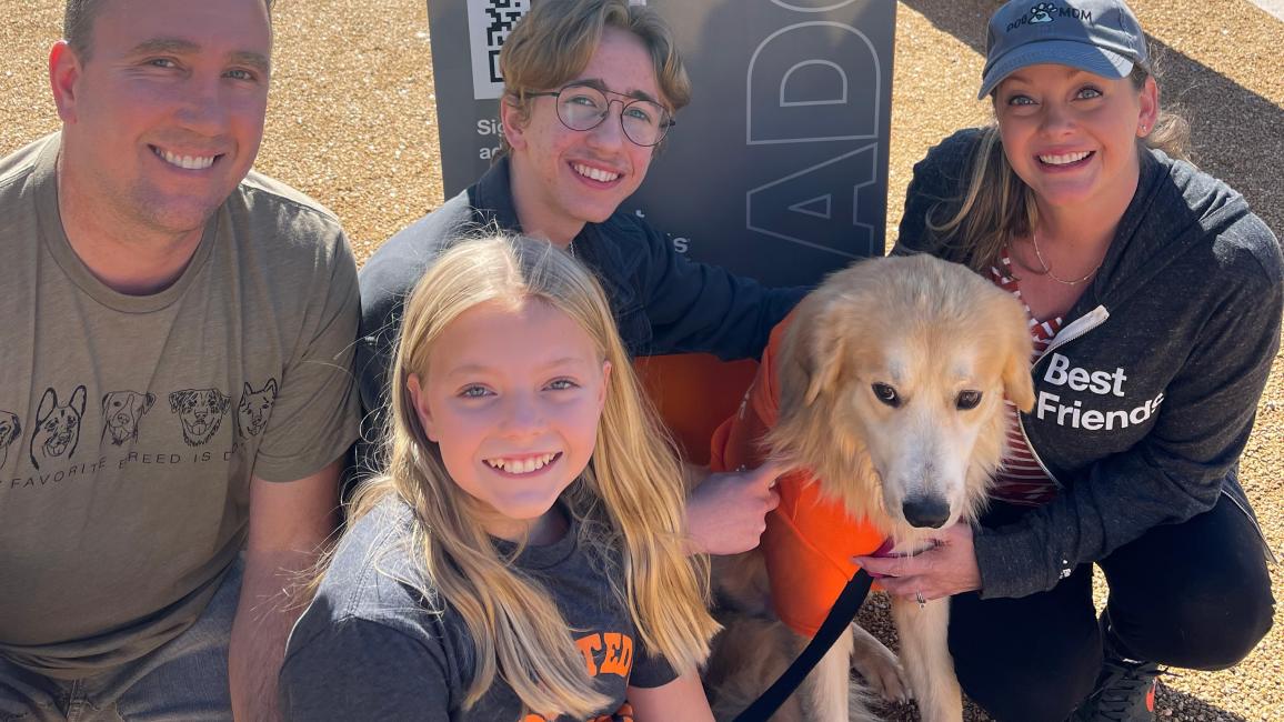Caesar the dog with his new family outside in front of a Best Friends sign