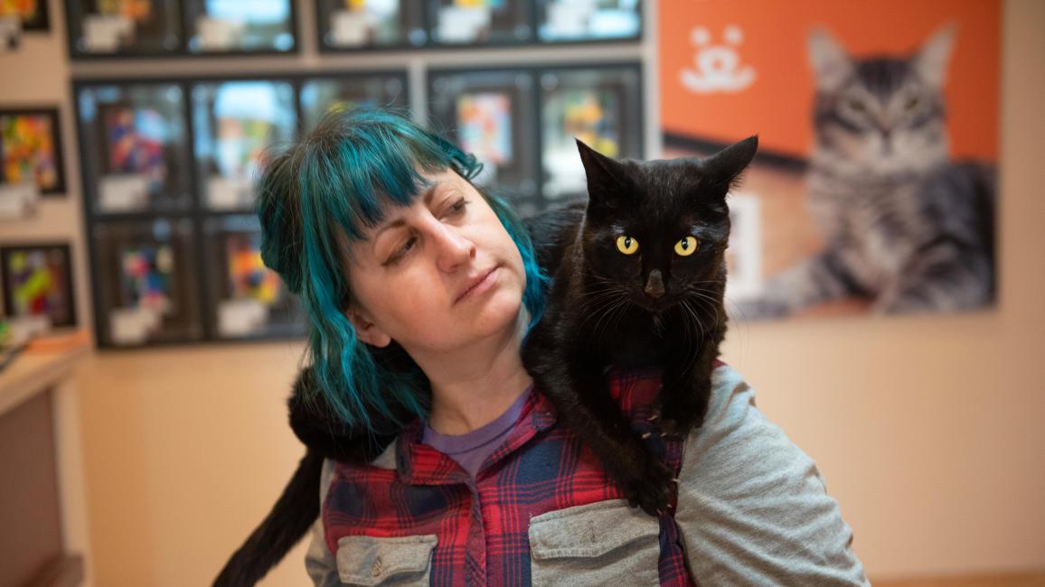 Samara the black cat sitting on her caregiver's shoulders