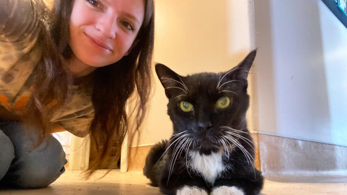 Petey the cat with Emily kneeling next to him