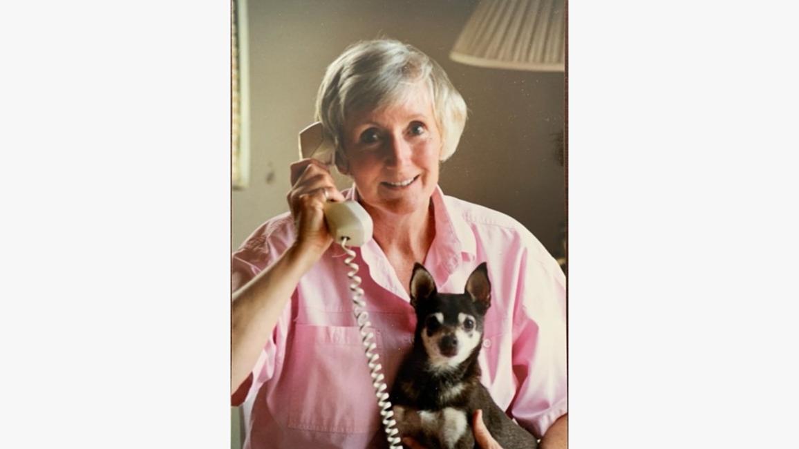 Best Friends co-founder Charity Rennie on a phone with a small dog in her lap