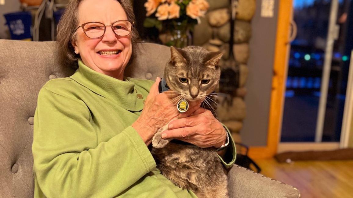 Cherri Gillmore sitting on a chair holding a gray tabby cat