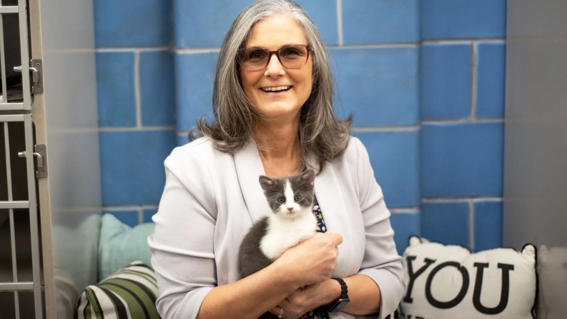 Smiling woman holding a gray and white kitten