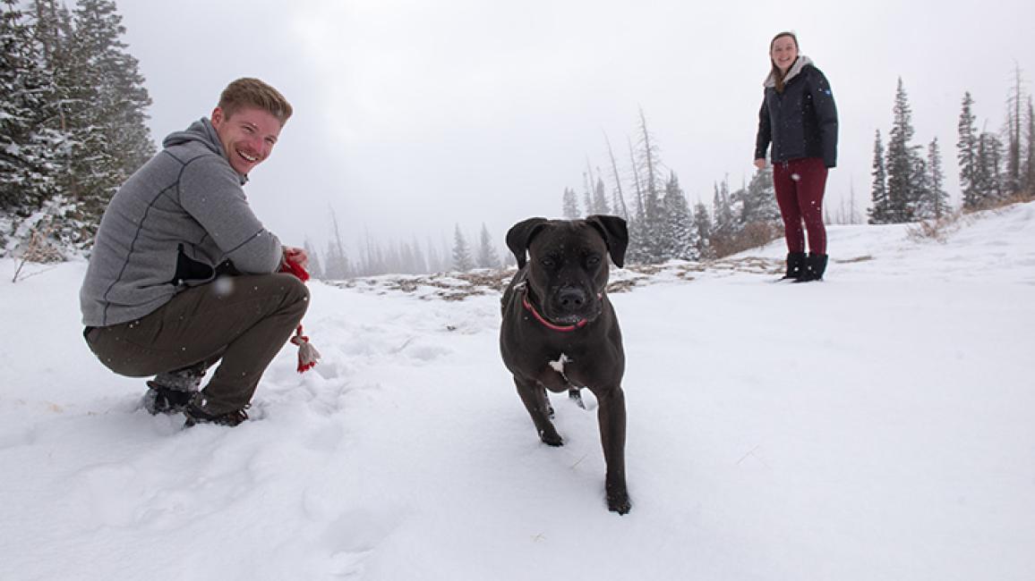 Dakota the dog outside in the snow with adopters