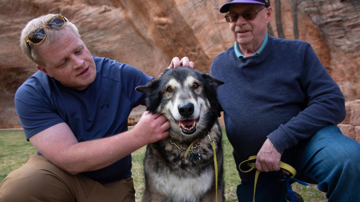 Shadow the dog with two people petting him