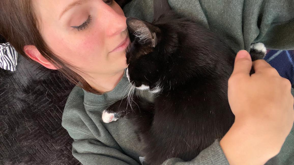 Emily snuggling with Hale the cat, face-to-face, with her arm around him