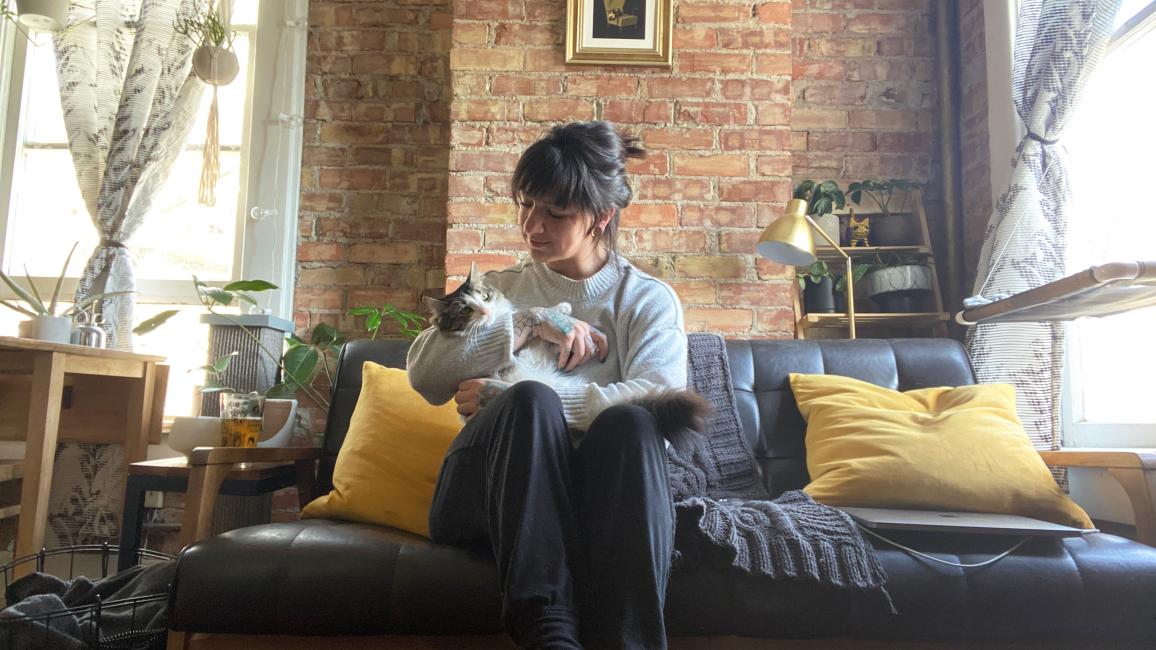 Paula holding Squeegee the cat while sitting on a couch