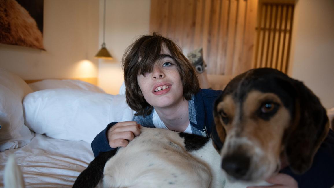 Gavin Spencer in bed on a sleepover with his arm around Blair the dog in a hug