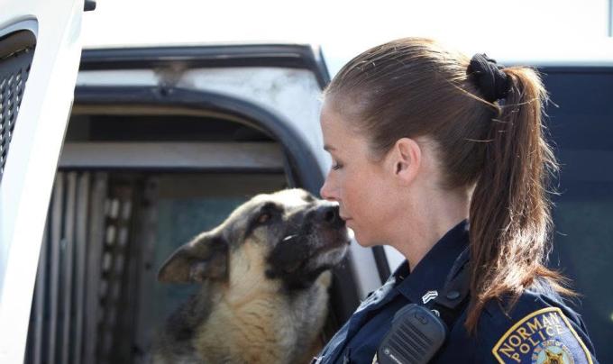 Kellee Robertson wearing a police uniform beside a shepherd dog