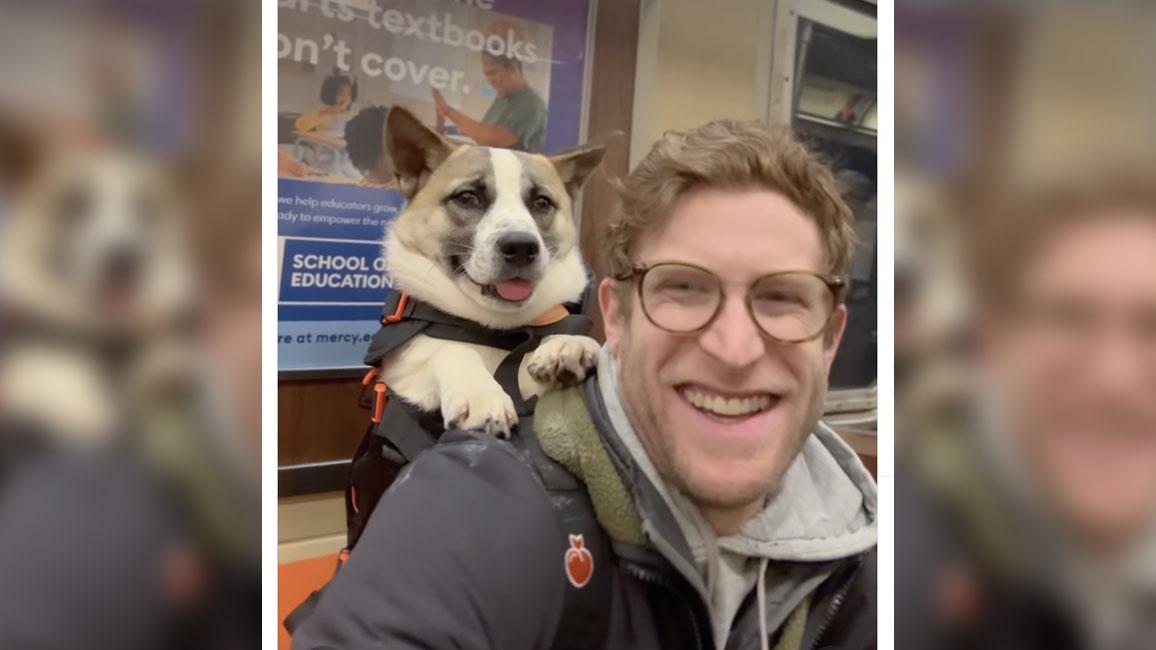 Bryan Reisberg smiling while carrying a dog in a backpack