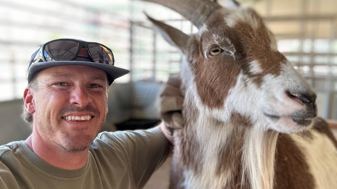 Smiling volunteer from the MenHealing group with a goat