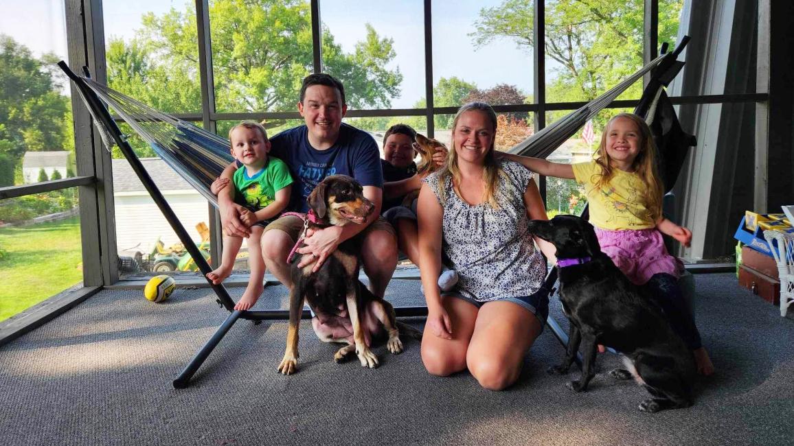 Family adopting Jewel the dog in front of a window