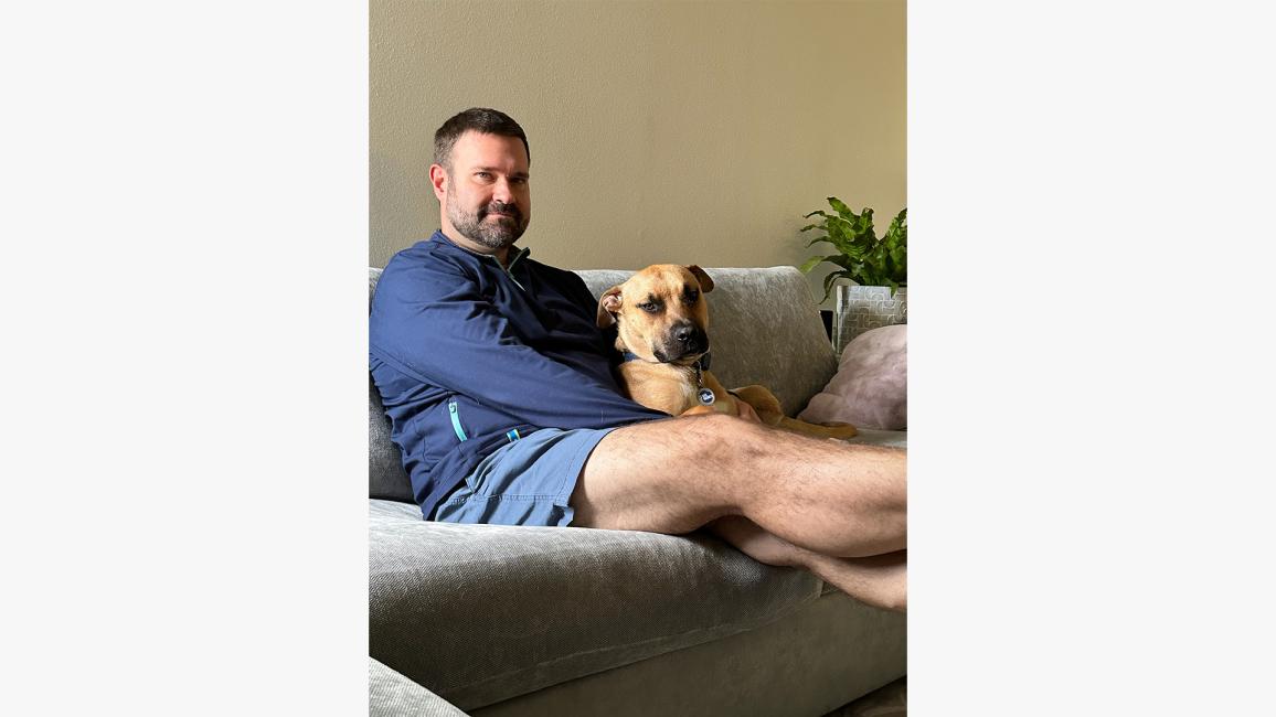 David Reilly sitting on a couch with Rex the dog