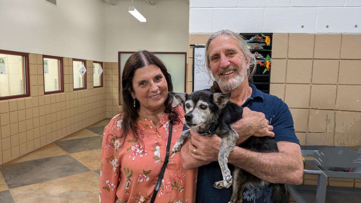 Andy the dog being adopted by two people