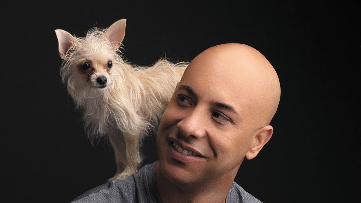 Dr. Kwane Stewart with a small dog on his shoulder