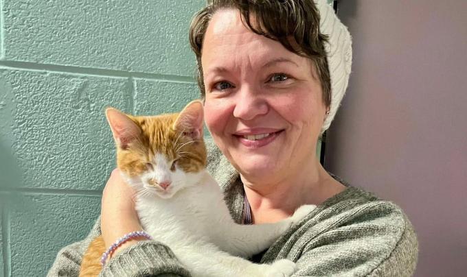 Lucky the cat being held by his adopter