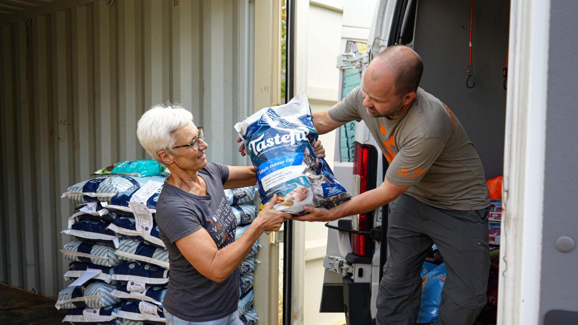 Volunteer Toni Dorsey and another person unloading pet food from a truck