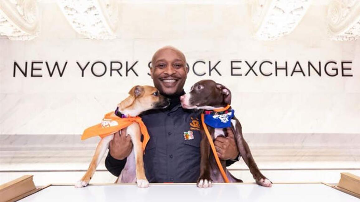 Marlan Roberts holding two puppies at the New York Stock Exchange