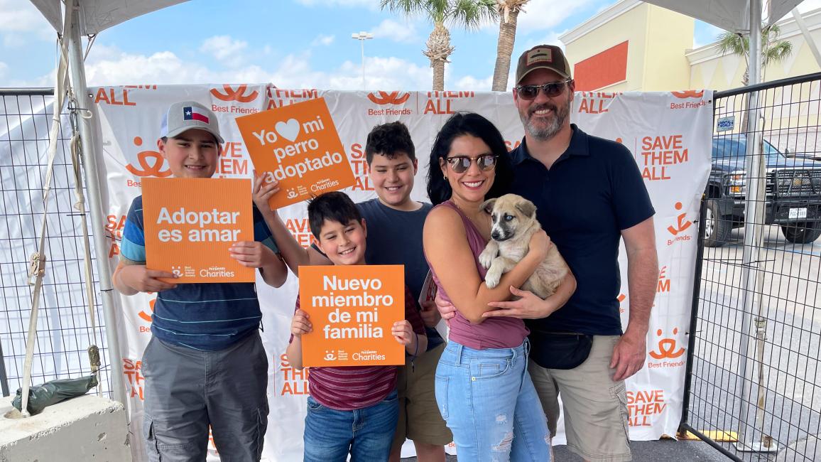 Family holding a puppy they adopted along with some Best Friends signs