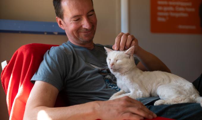 Mike Lorrig petting Bae the cat in his lap