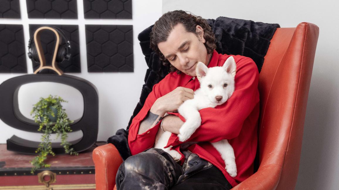 Gavin Rossdale sitting in a chair holding a white puppy