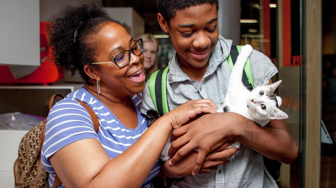 Two people smiling and holding a white and gray kitten