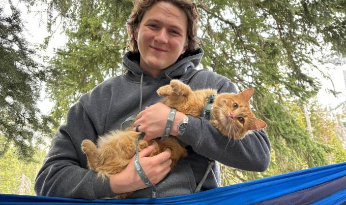 Ali holding an orange tabby cat while outside