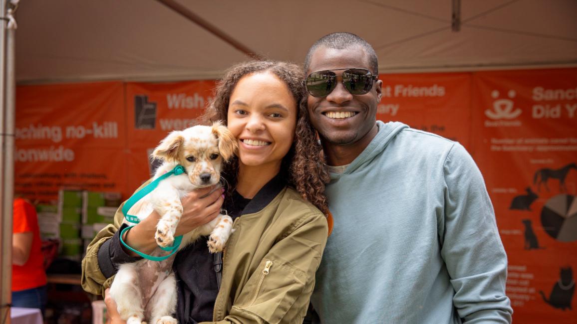 Smiling couple holding a puppy who they adopted at the NKLA Super Adoption
