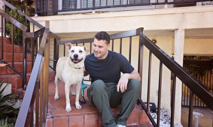 Dog and person sitting on outside steps at a housing complex
