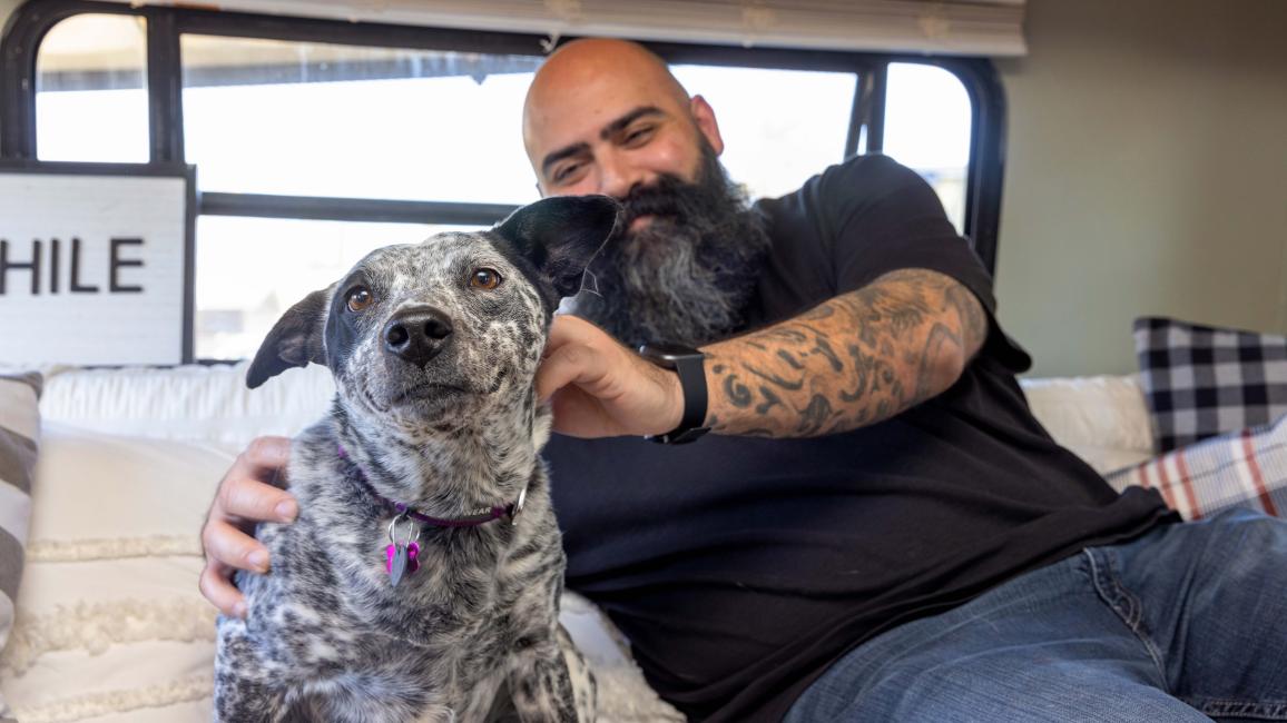 Chris Alton sitting next to a dog in their RV