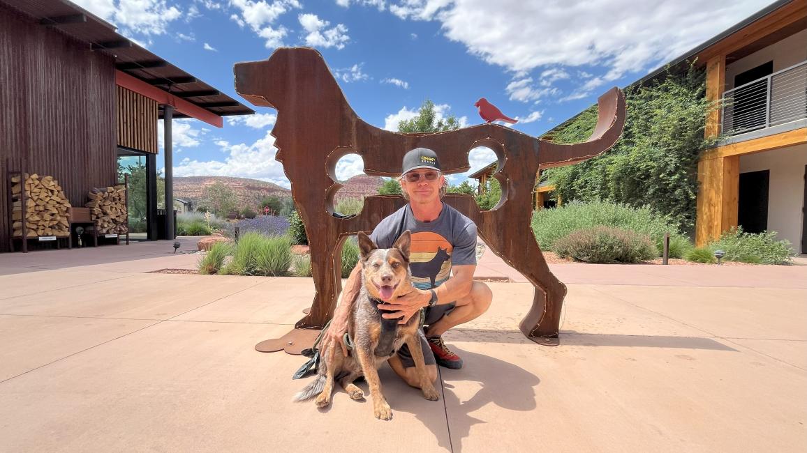 J.J. McMahon and Whitey the dog in front of a metal sculpture of a dog at the Roadhouse