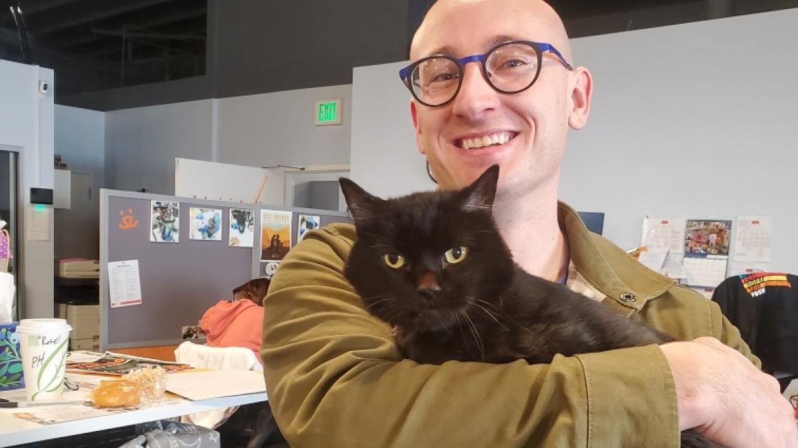 Smiling person holding Fossey the black cat