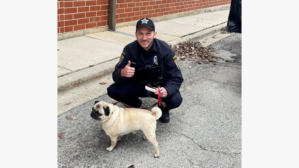 Community service officer Sean Bus giving a thumbs up sign with Wilson the pug