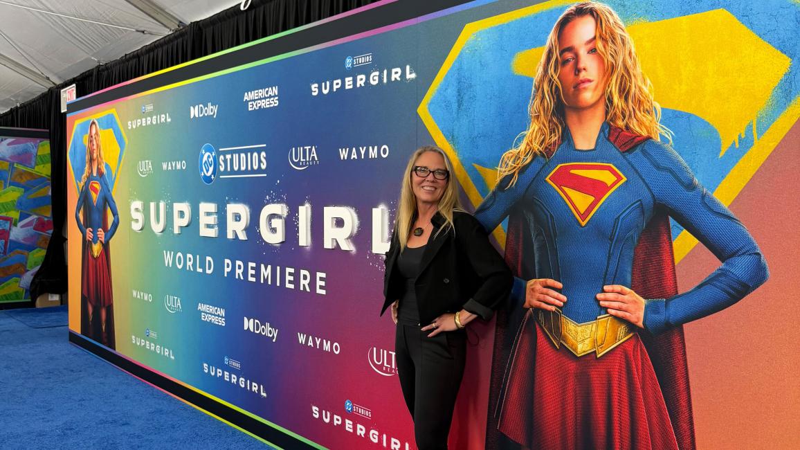 Best Friends CEO Julie Castle in front of a Supergirl world premiere sign