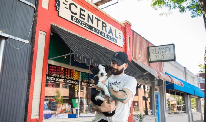 Calvin holding Sylvia the puppy in front of Central Book Exchange