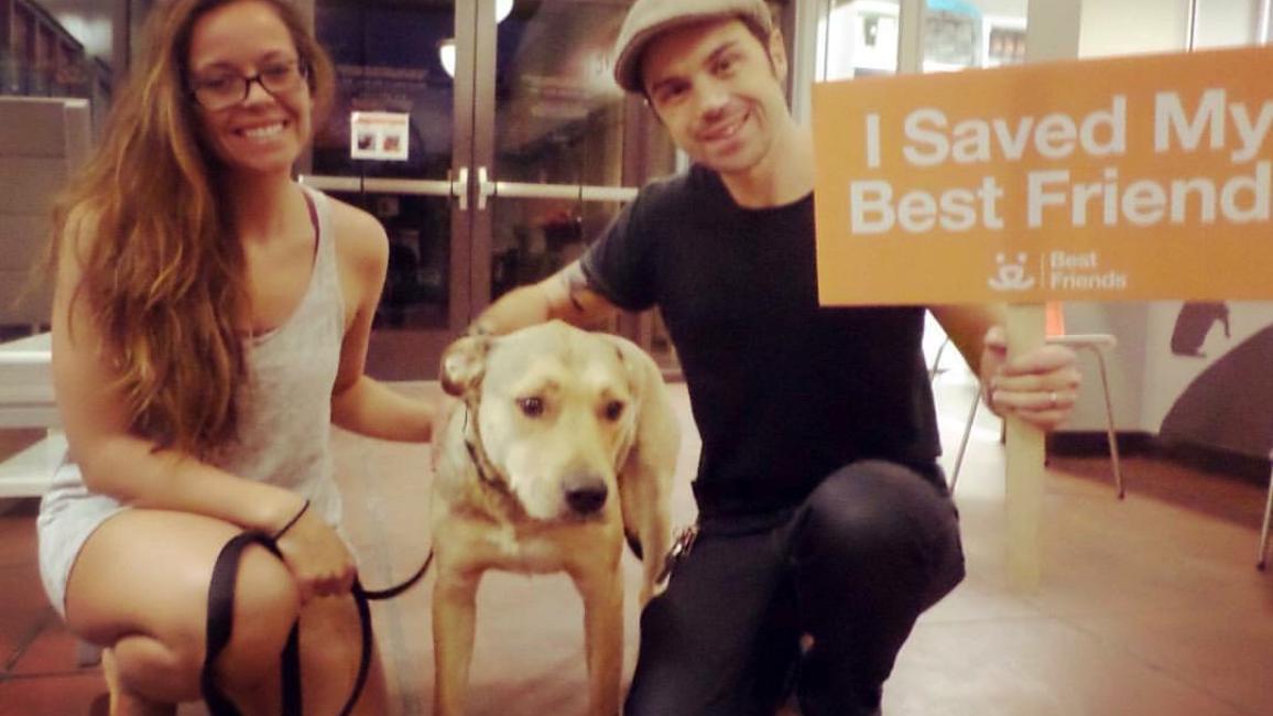 Erik Smith and a woman adopting Nash the dog, holding a 'I saved my best friend' sign