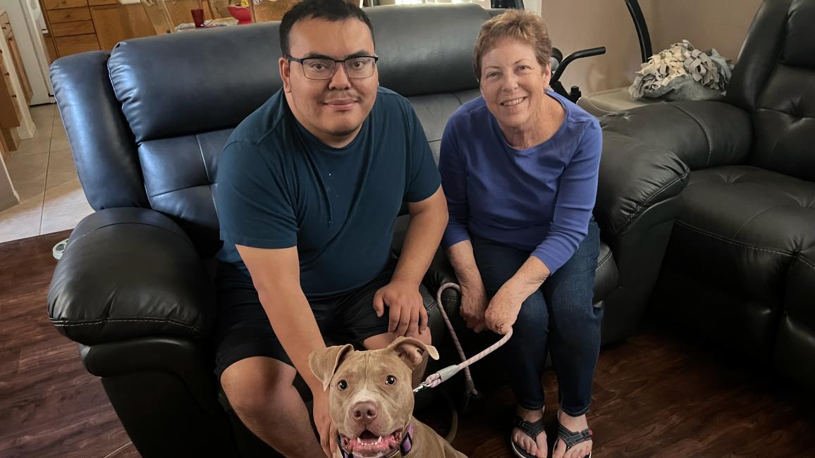Ginny and Kenny Popvich with posing on a loveseat with a dog