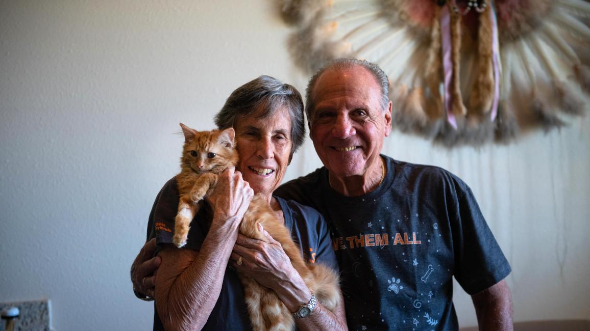 Brenda and Marty Winnick smiling and holding an orange tabby cat