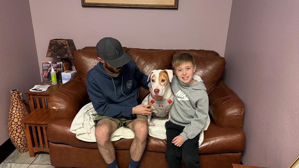 Mona the dog on a couch with her family