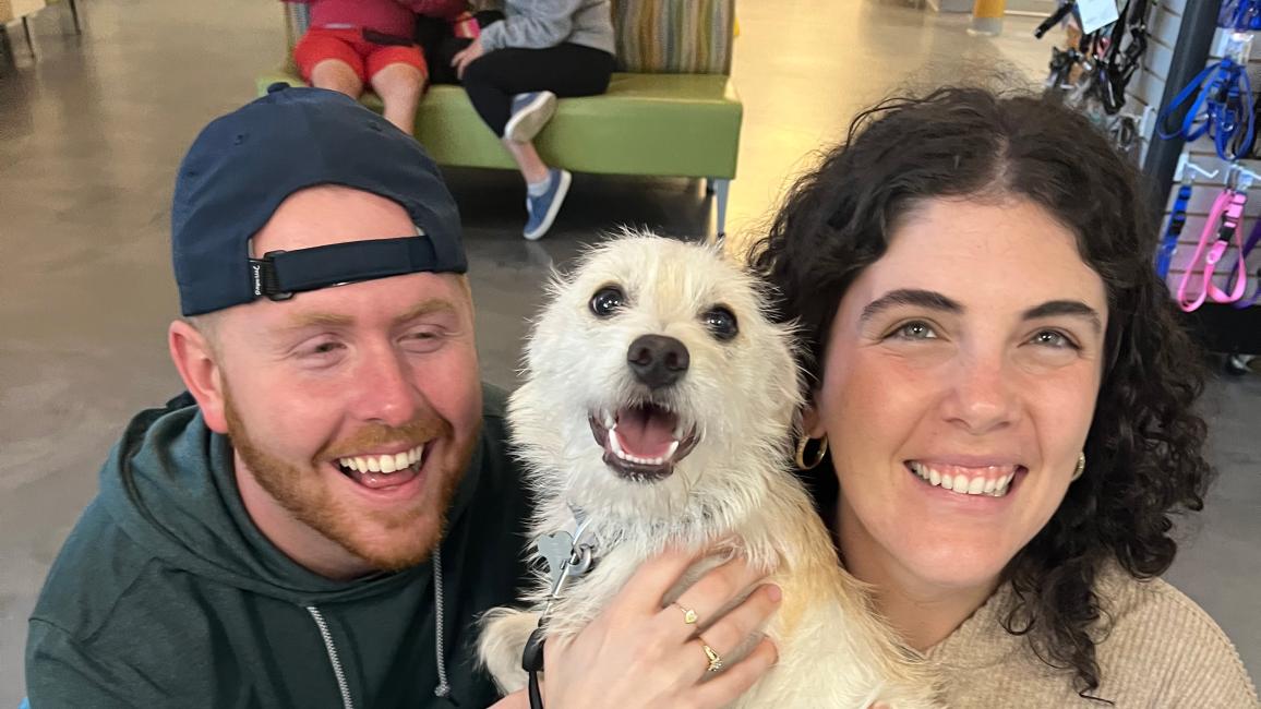 Happy couple holding a small white dog they'd adopted