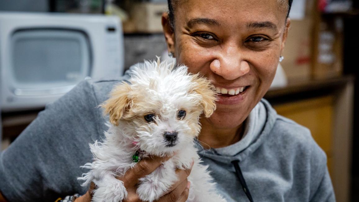Tammie Sadler smiling and holding Bella the Maltese-mix puppy