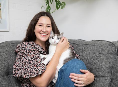 Person sitting on a couch and hugging the cat she adopted