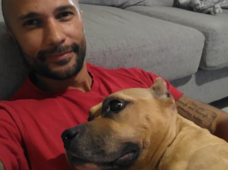 Alex Contreras hugging a brown dog with cropped ears