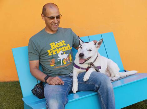 Volunteer Robert Lobo wearing a Best Friends T-shirt and sitting with a dog on a blue chair