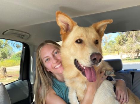 Emma hugging Archie the dog  in the back seat of a vehicle