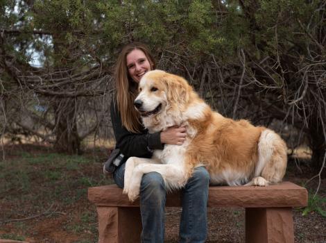 Person sitting on a bench while Bear the dog lies in her lap
