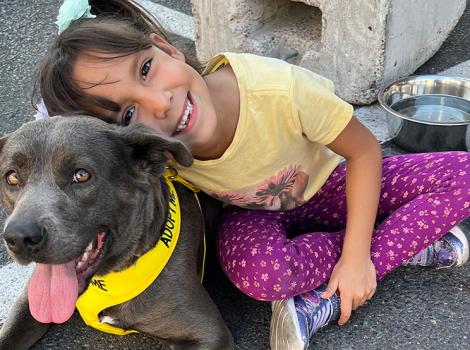 Child smiling and head leaning into happy looking dog