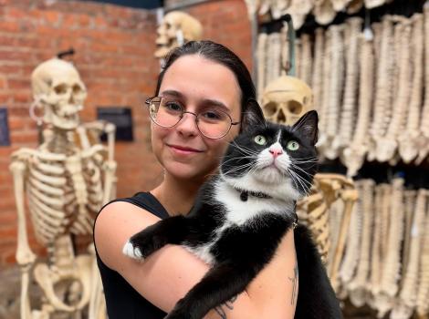 Person holding Bone Jovi the cat in front of some human skeletons