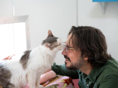 Bubba the cat sniffing Jesse the caregiver's face