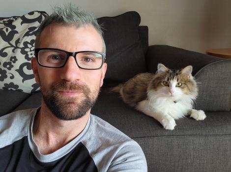 Dolly Parton the cat lying on a couch behind Scott