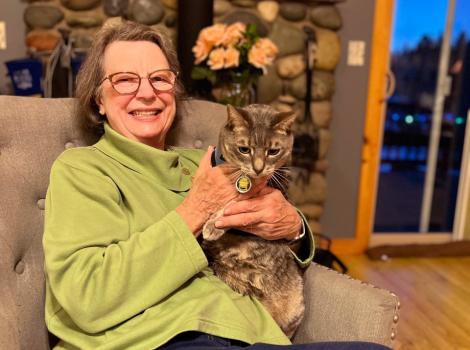 Cherri Gillmore sitting on a chair holding a gray tabby cat